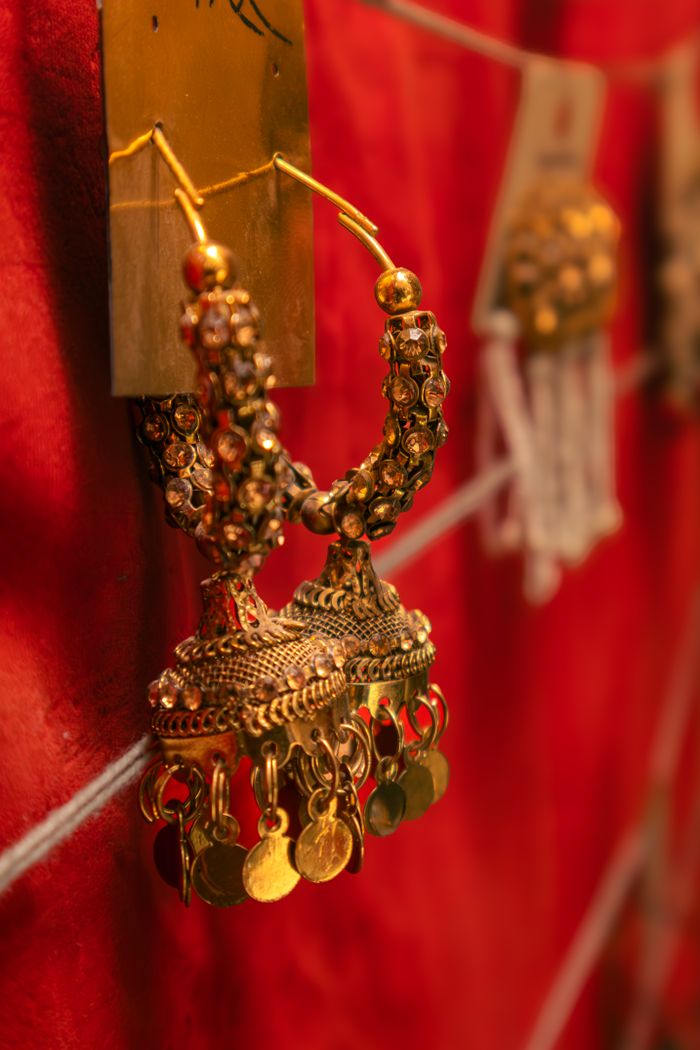 Close-up of ornate traditional Indian earrings set against a rich red background, showcasing intricate details.